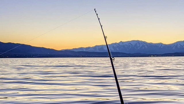 Calm water at Utah Lake at sunset, with a fishing line cast