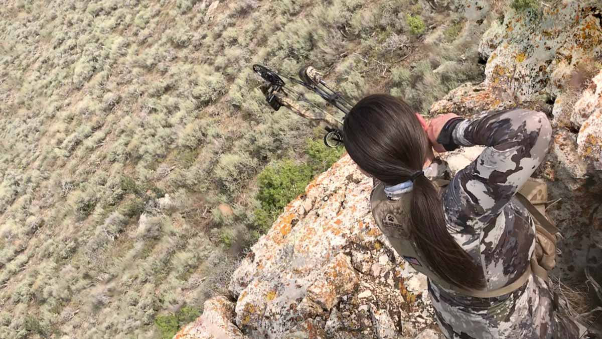 Heidi Heckethorn aiming her bow and arrow at game in an open field