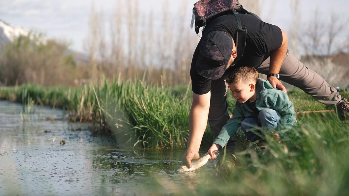 Joe Sanchez and his young son holding a fish in the water