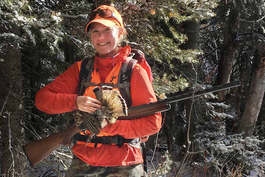 Melissa Early holding a rifle and a harvested turkey