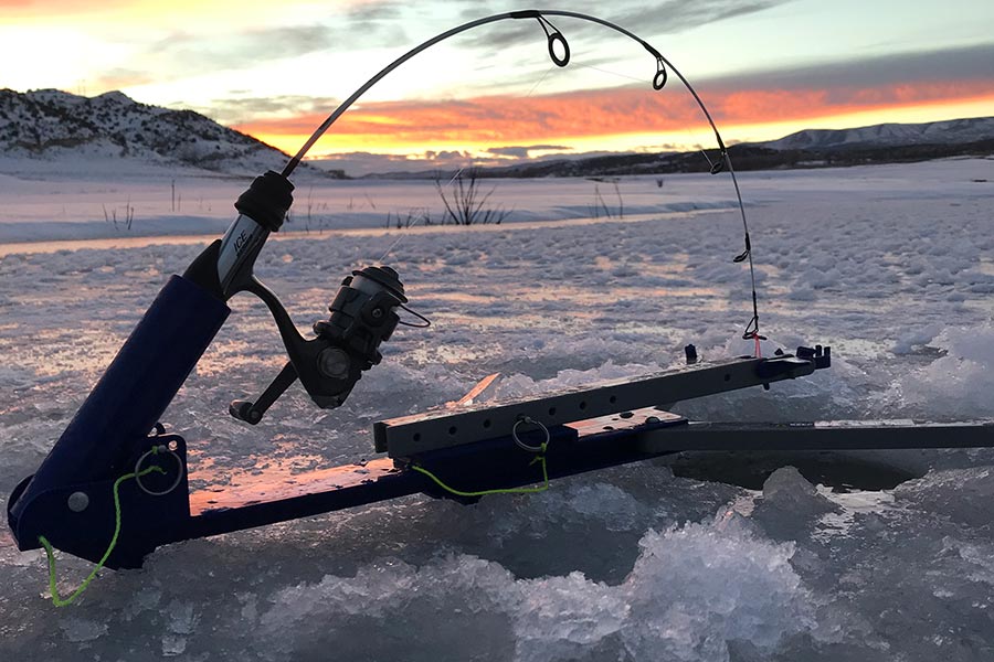 Fishing pole set up in a hole in a drilled hole in the ice, at sunset