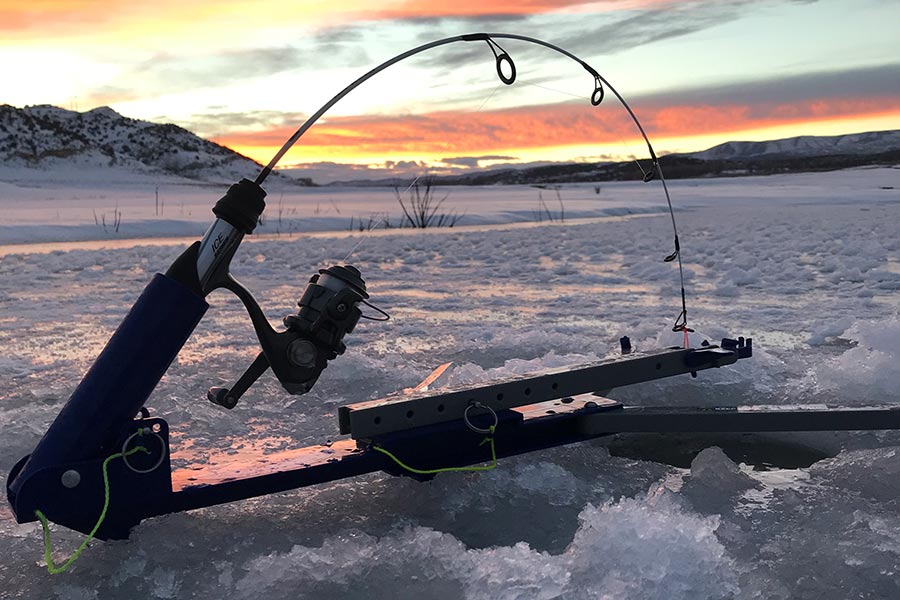 Fishing pole set up in a hole in a drilled hole in the ice, at sunset