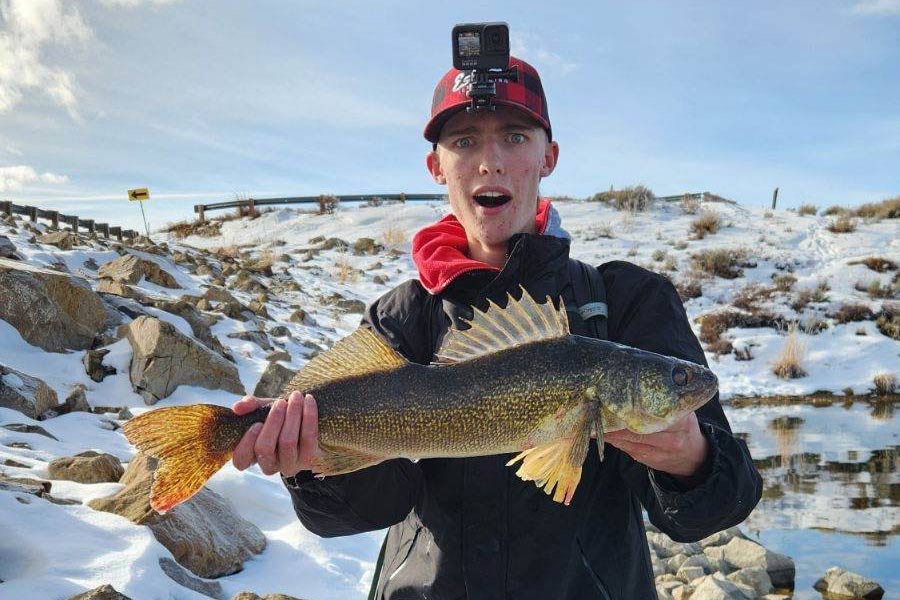 Sam Broderick holding a caught walleye fish at Strawberry Reservoir that was illegally introduced